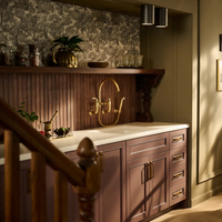 Brizo Faircroft wall-mount bridge faucet and side spray in in a traditional kitchen with wood paneling and custom cabinetry