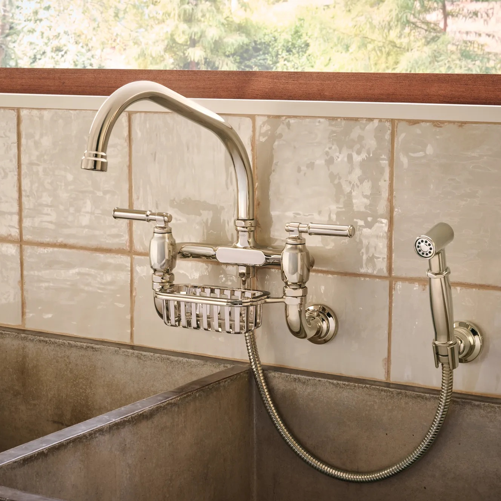 Brizo Faircroft wall-mount bridge faucet and side spray with integrated soap basket over a farmhouse sink.
