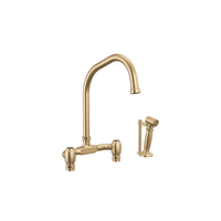 Brizo Faircroft deck-mount bridge faucet with angled spout and side spray in luxe gold finish