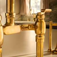 Close-up shot of Brizo Faircroft deck-mount bridge faucet and side spray in unlacquered bass