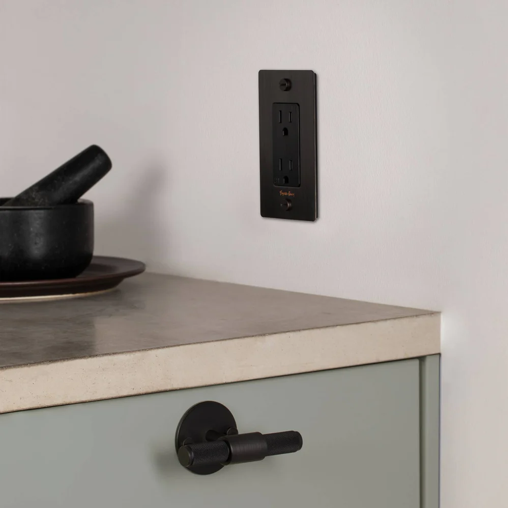 Buster and Punch 1 Gang Cross Outlet in Black with logo on wall in kitchen.