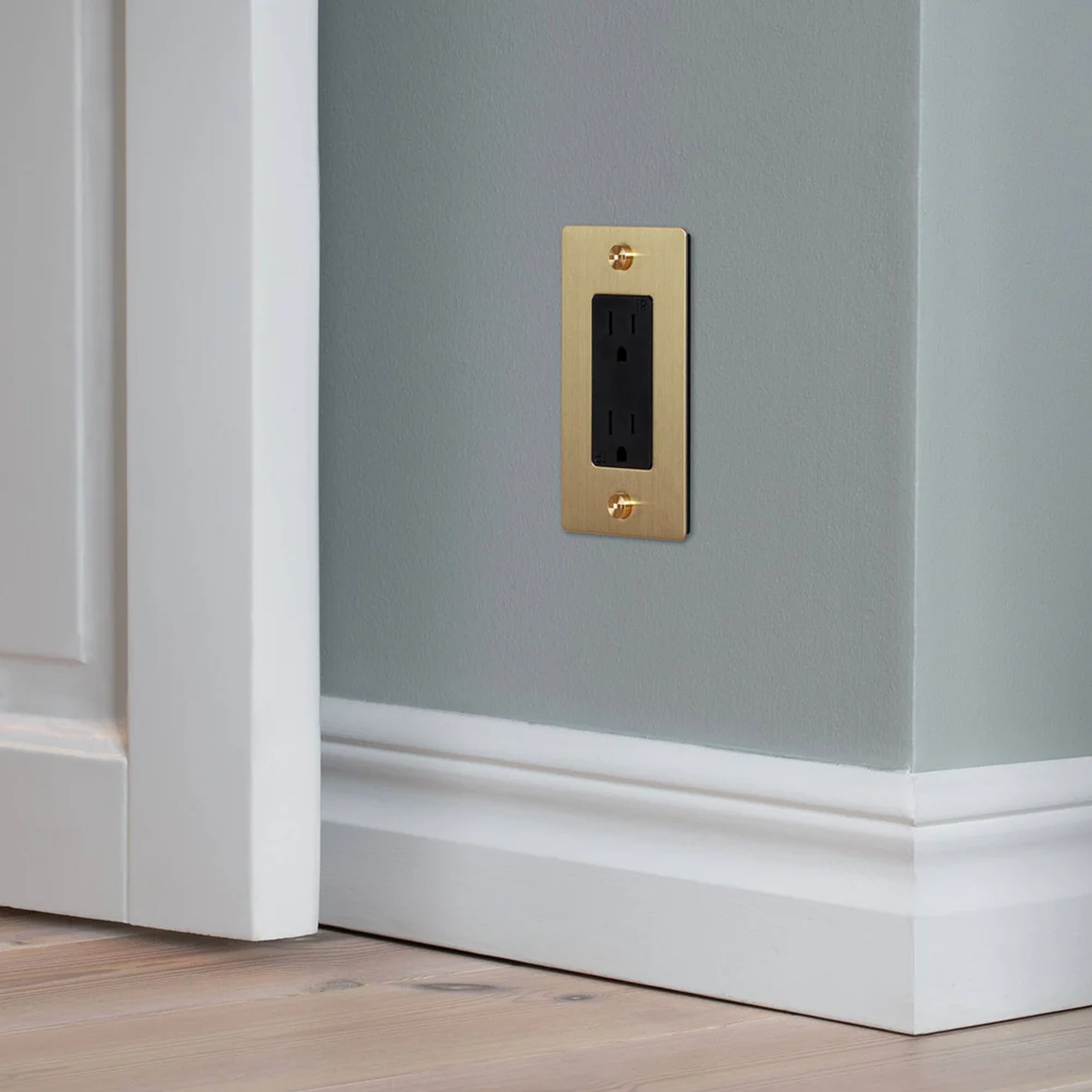 Buster and Punch 1 Gang Cross Outlet in Brass with logo on wall.