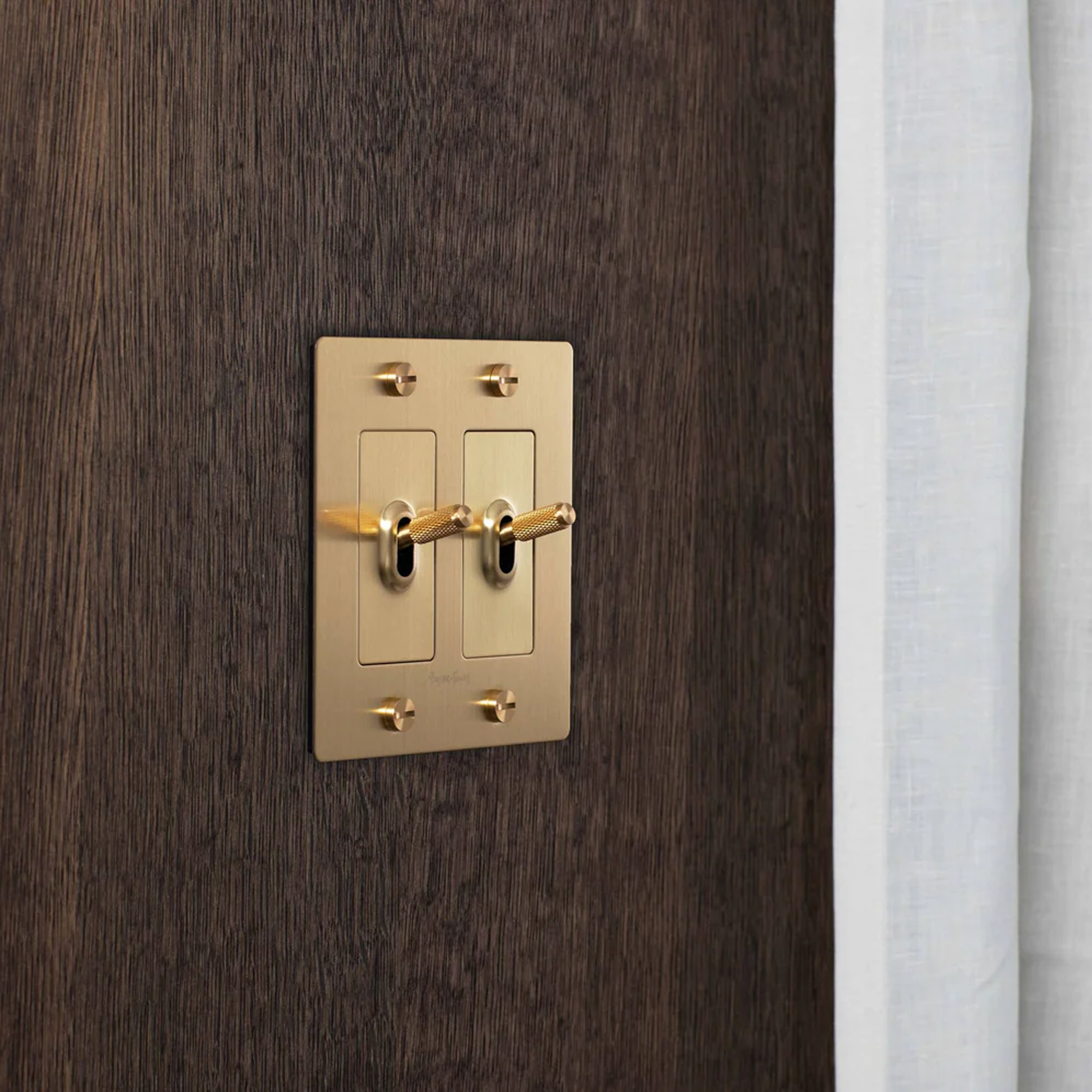 Buster & Punch Brass Light Switch 2 Gang Toggle with Cross design on wall