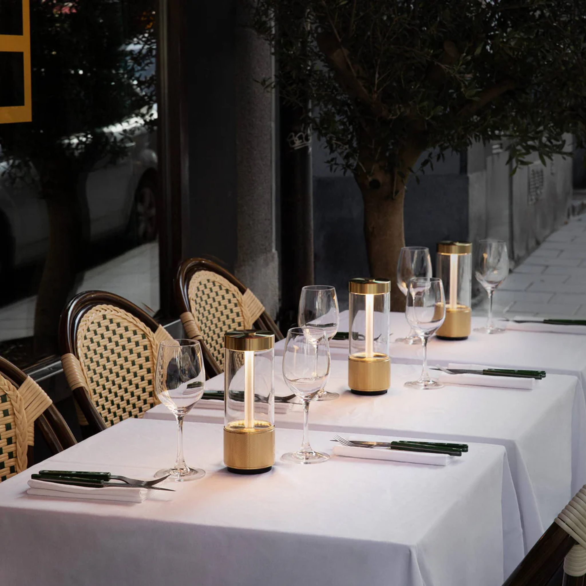 Elegant outdoor dining setup with brass gold decorative Buster and Punch Takeout table lamps.
