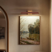 Framed landscape painting illuminated by a modern Alora Gemma Wall/ Picture Light 