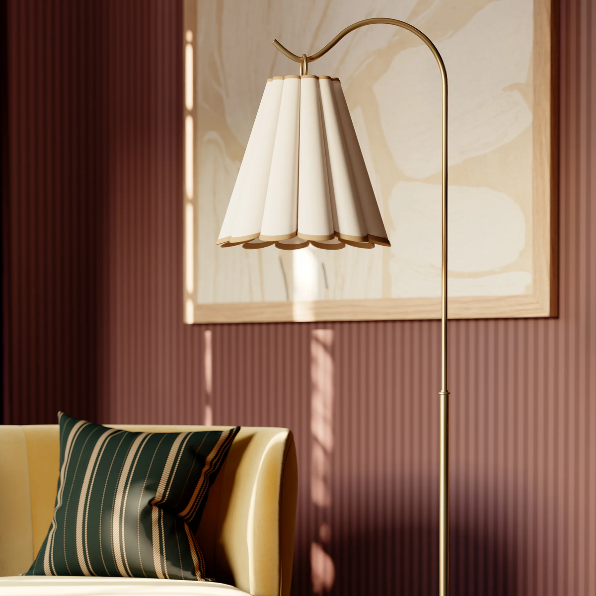 A close-up of a modern Eula floor lamp with a curved brass stand and a pleated cream shade in a livingroom.