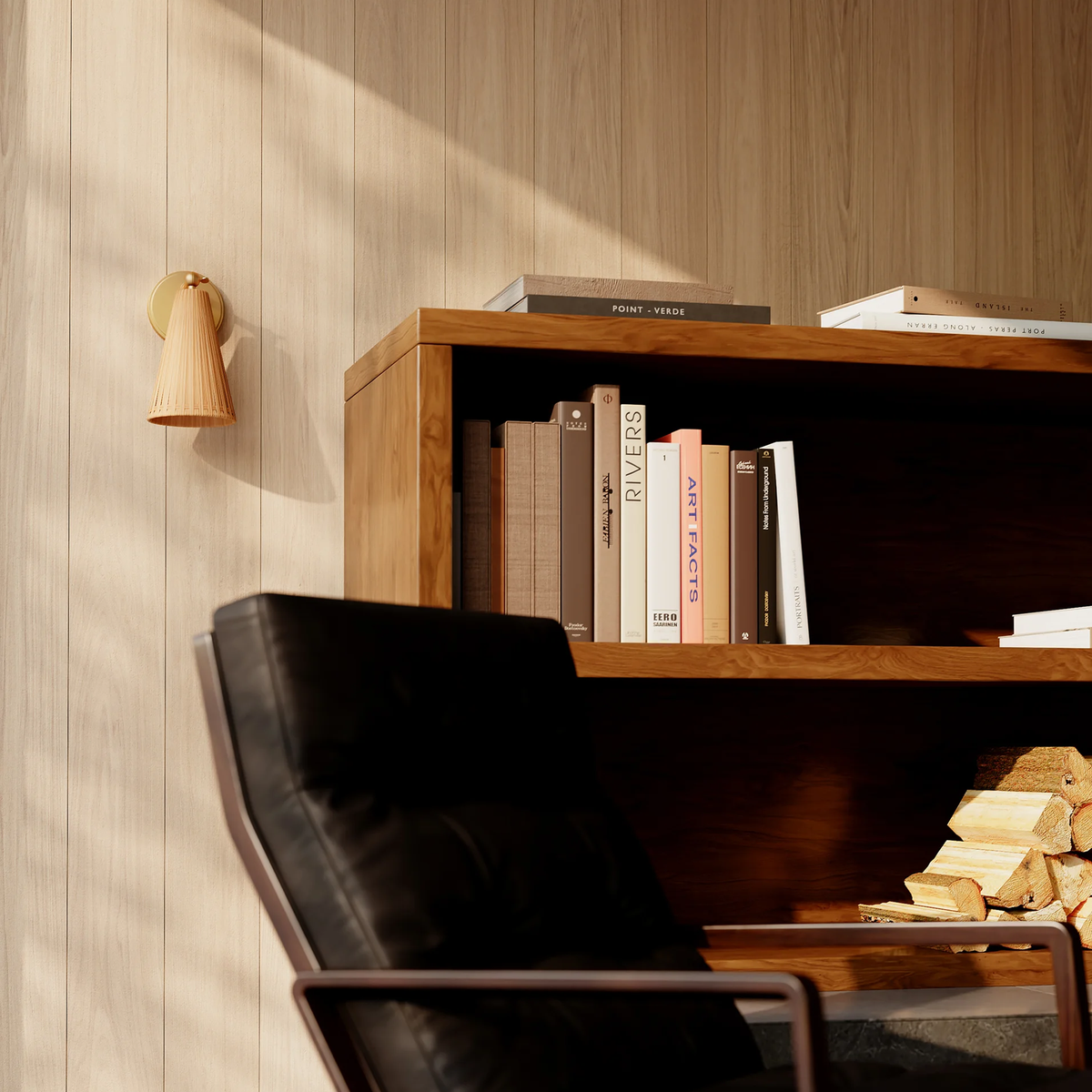A wood-paneled wall with a Griffith wall sconce by Hudson Valley, a wooden bookshelf holding books and a black leather chair.