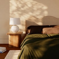 Bedroom setting with beige scalloped headboard and wooden side table with Karina table lamp