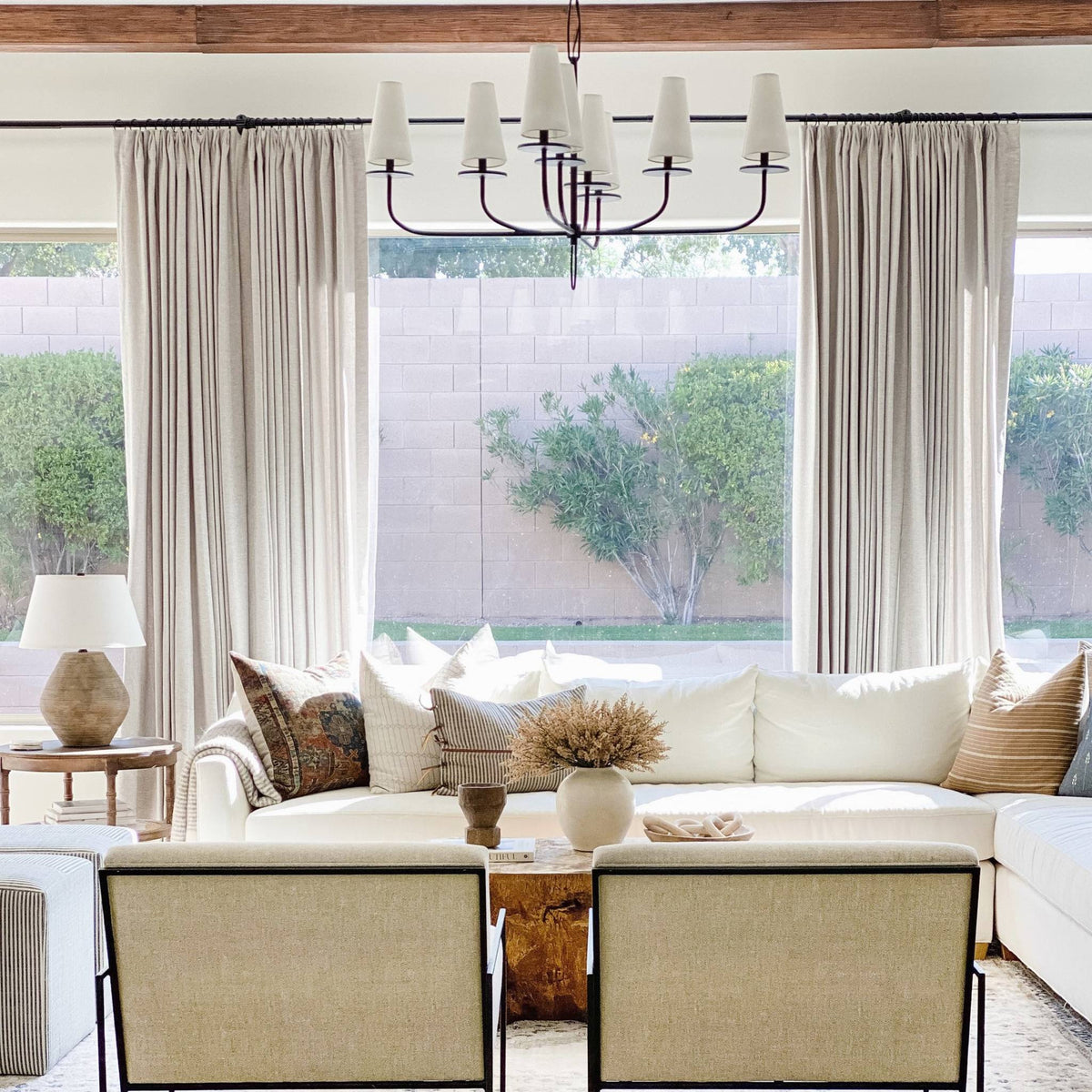 A styled living room interior featuring a large cream sectional sofa with beige and patterned pillows, and Calabria Table Lamp