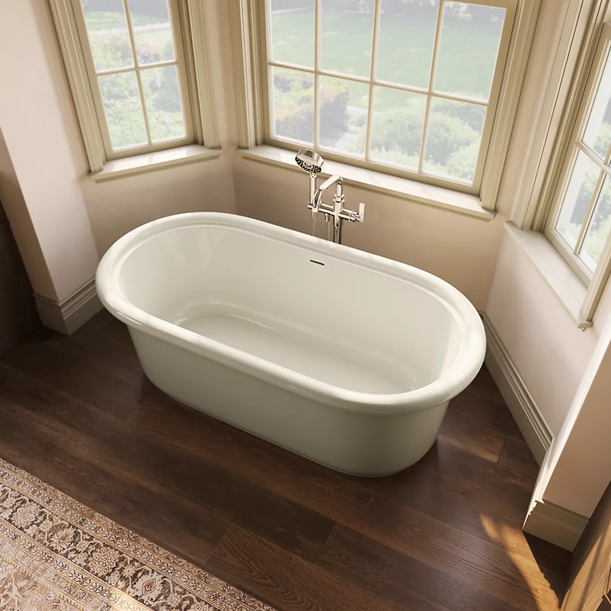 Claude™ freestanding bathtub by Kohler in bright white finish shown installed in bathroom in front of windows.