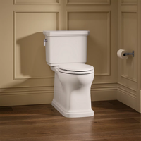 Claude™ two-piece elongated toilet in white by Kohler shown installed in bathroom with wood flooring.