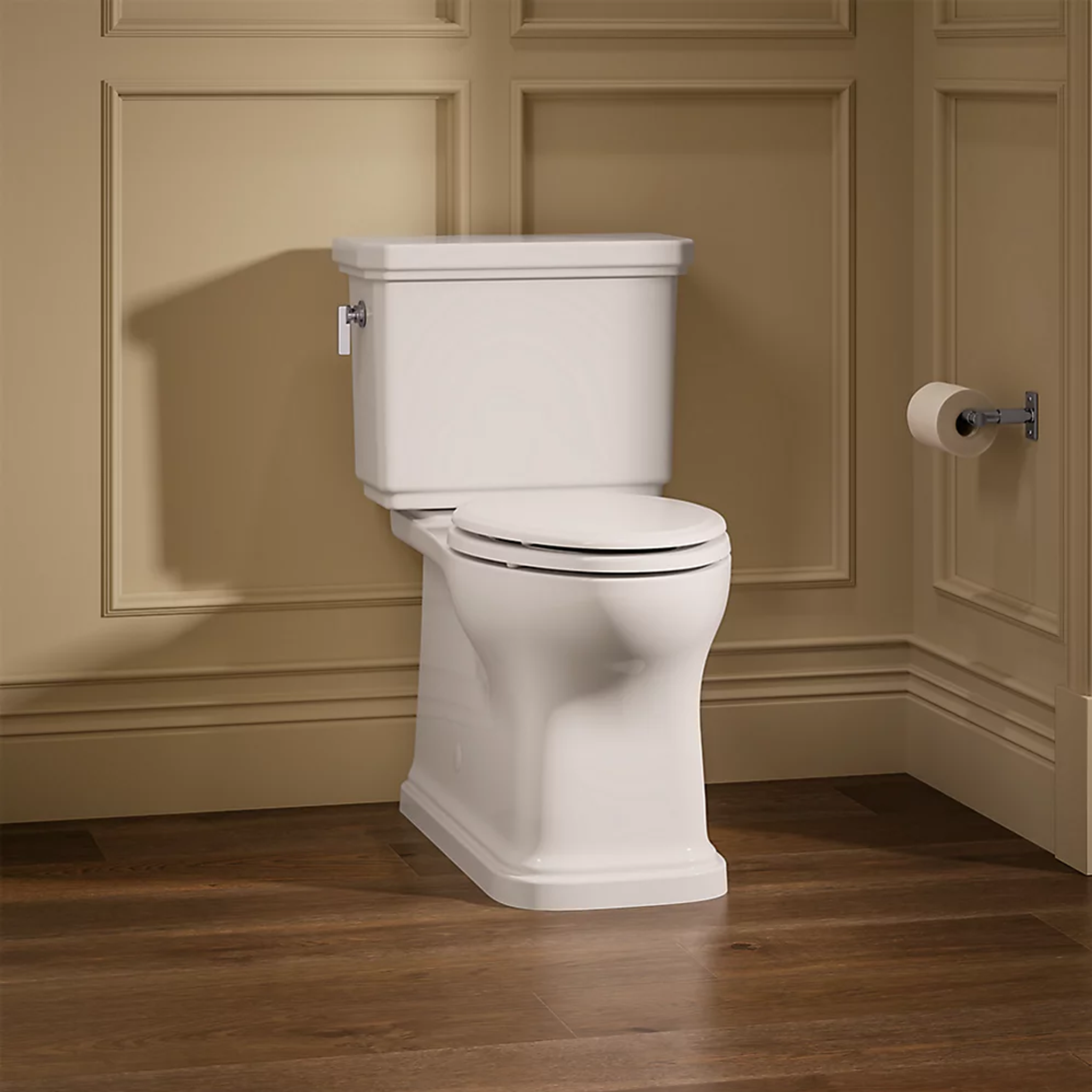 Claude™ two-piece elongated toilet in white by Kohler shown installed in bathroom with wood flooring.