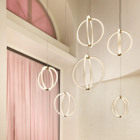Six Luminora pendant lights hanging in a room with pink curtains.