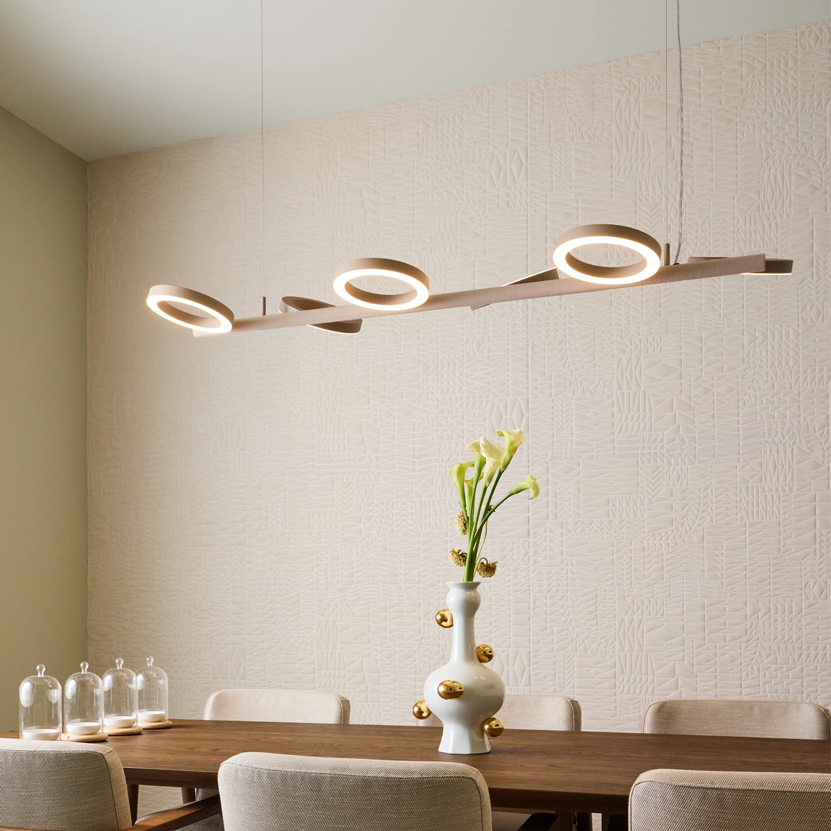 Dining room with a Pallana pendant light fixture, table, chairs, and a vase with flowers.