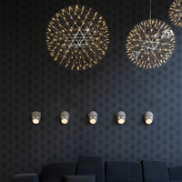 Moooi chandelier and the Party wall light collection against a dark patterned wall.