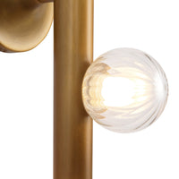 Close-up view of Kuzco Reese Wall Sconce in vintage brass with clear glass globe