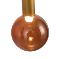 Close-up view of Kuzco Reese wall sconce with vintage brass finish and amber glass globe