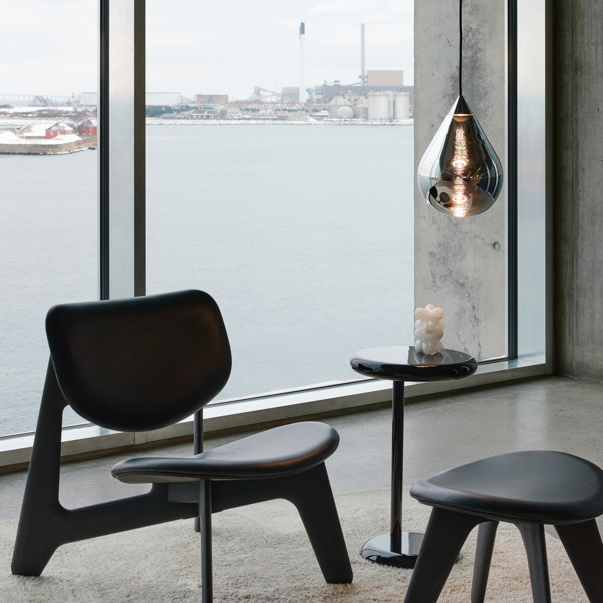 Tom Dixon Flare Pendant in silver hanging near window with modern black chair and stool