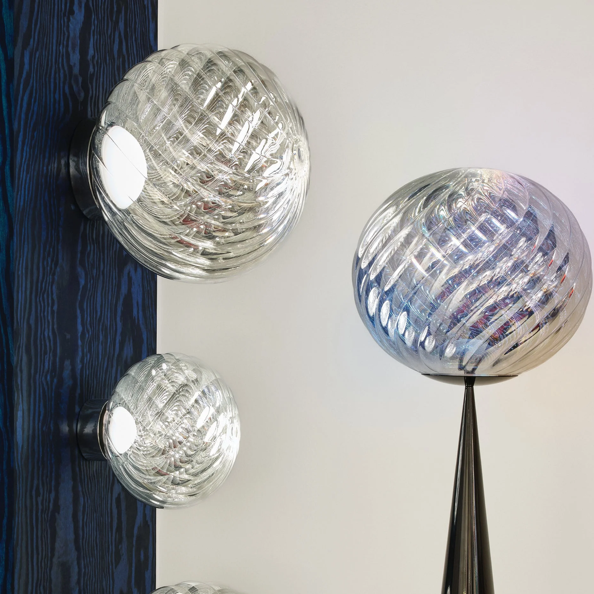 Two Tom Dixon Whirl LED Wall Lights in silver finish beside a Whirl Table Lamp.