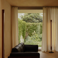 Two Flos Seki-Han floor lamps positioned beside a black leather sofa and floor-to-ceiling curtains in cozy living room.