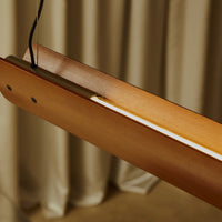 Close-up detail of Flos Seki-Han suspension light, crafted from warm-toned wood, featuring an integrated LED light strip recessed along the center.