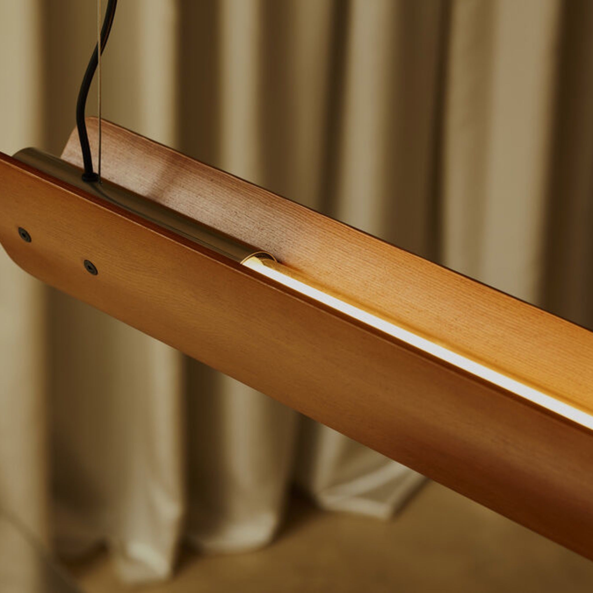 Close-up detail of Flos Seki-Han suspension light, crafted from warm-toned wood, featuring an integrated LED light strip recessed along the center.
