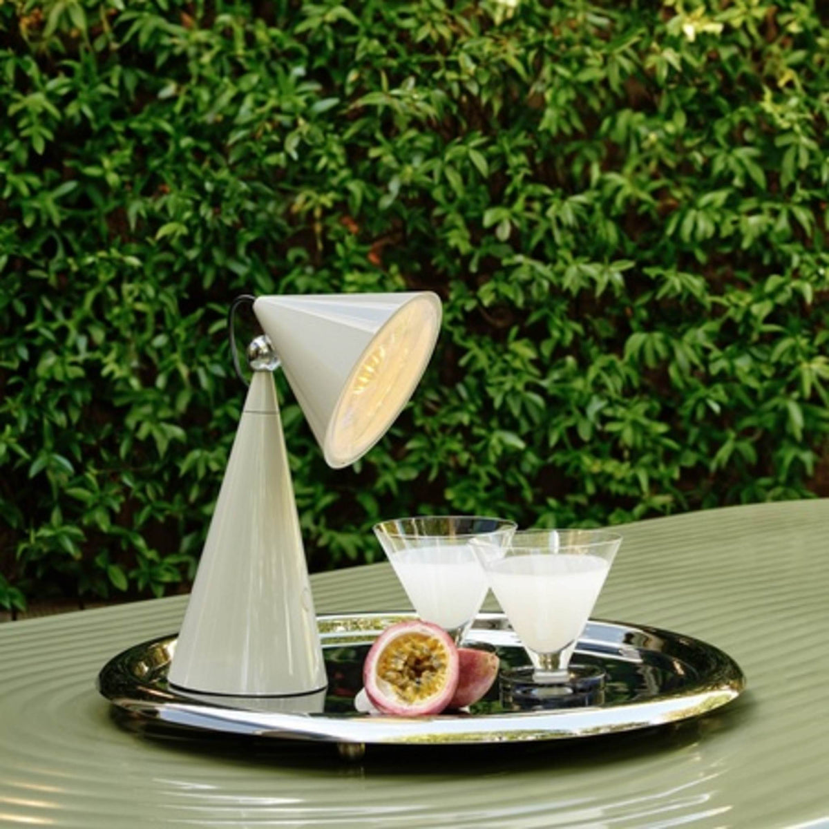 Modern cone-shaped table lamp on tray with drinks and passion fruit
